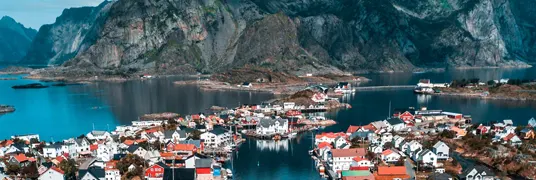 Mountainous island surrounded by city and boats