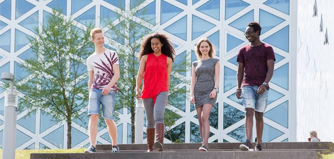 Four students walking outside a university campus building