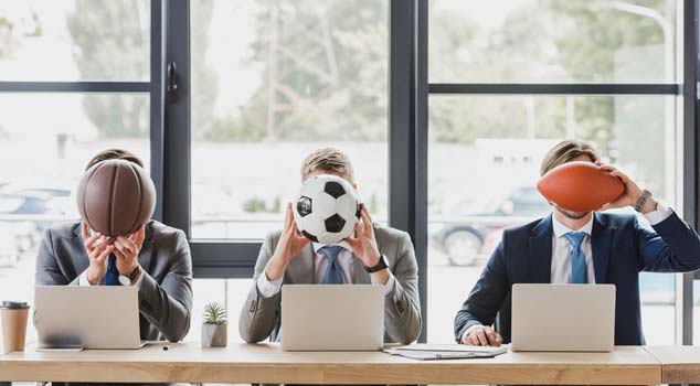 Three men holding sports balls to cover their faces