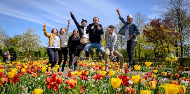 Jumping group of students with red and yellow tulips