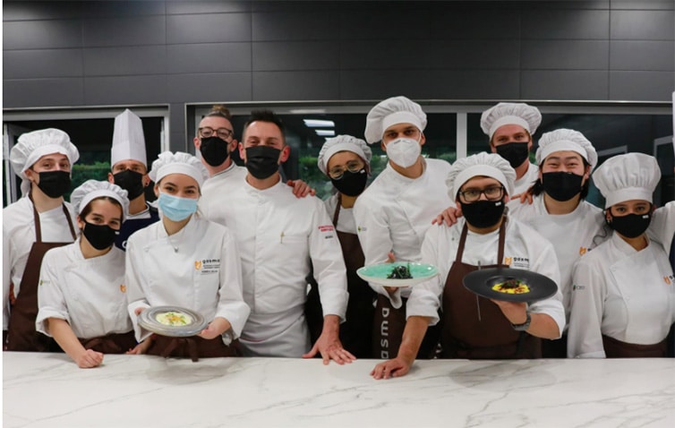 Culinary arts students in a professional kitchen showing their completed dishes