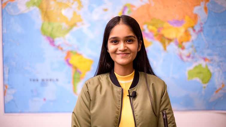 Smiling student in front of world map