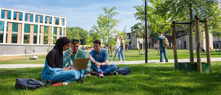 Students sitting outside around a laptop