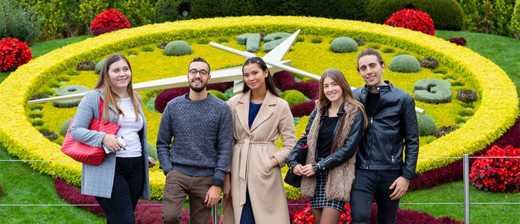 Students standing in front of floral clock display