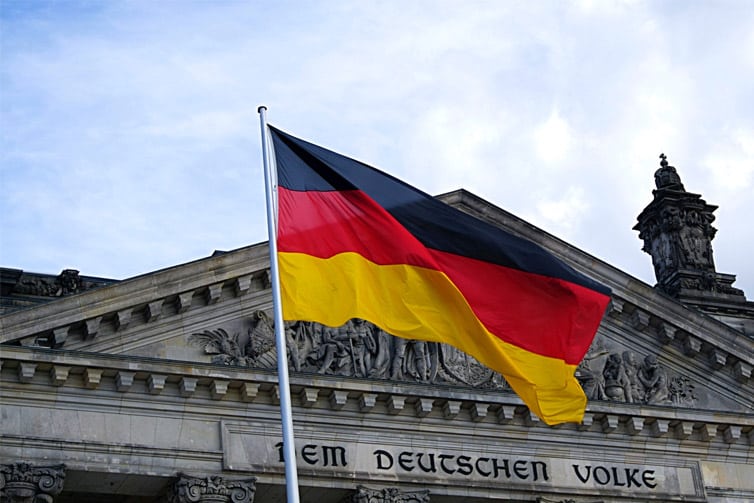 Image of the German flag flying on a flagpole in front of a building