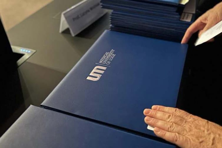 Image of a blue folder that has the logo and name of the Medical University of Lodz printed on it