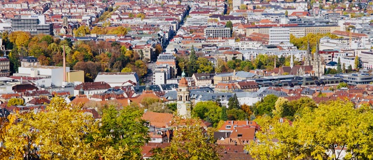 View of Stuttgart city buildings with green and orange treetops in the foreground