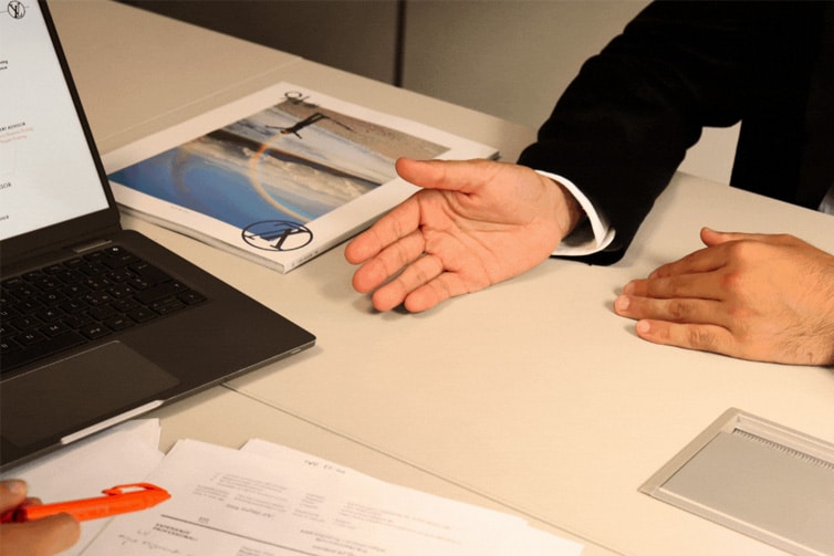 Image of a laptop, magazine and the hands of a person