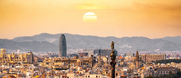 Image of the skyline of Barcelona with mountains and a yellow sunset sky in the background