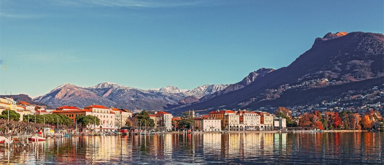 Image of a lake, with buildings and mountains in the background