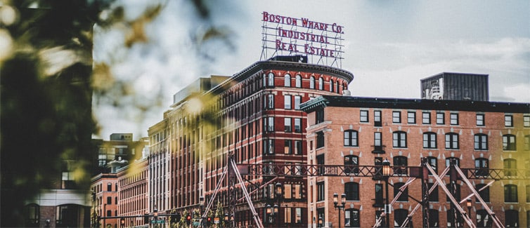 Red brick building with a big vintage style sign on top that reads Boston Wharf Co. Industrial Real Estate