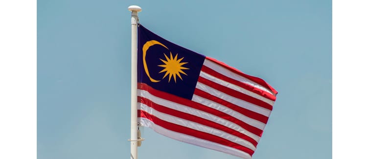 Image of a red, white, blue and yellow Malaysia flag on a flagpole