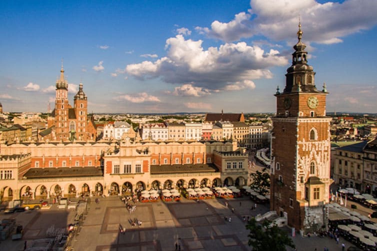 Large clock tower surrounded by other red brick buildings and a blue sky