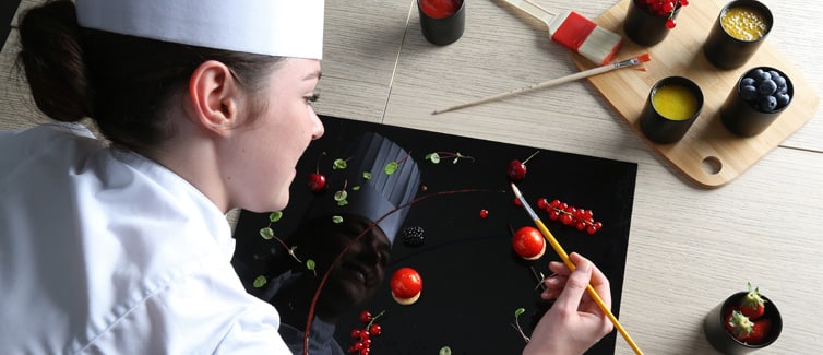 Student using food to decorate a large black plate