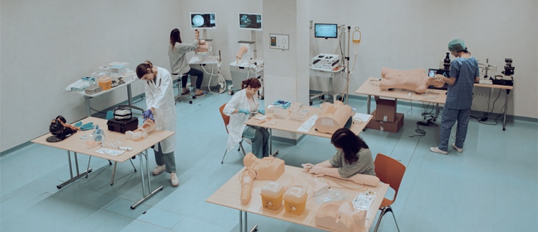 Image of students standing at tables with cpr dummies on them