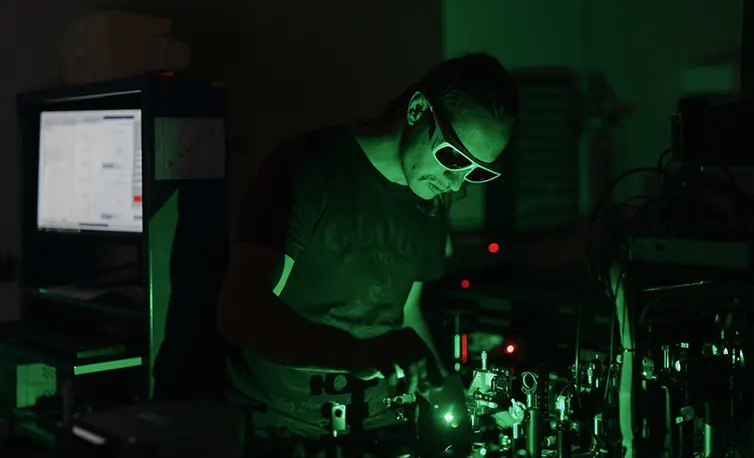 Man working in dark room with green lasers