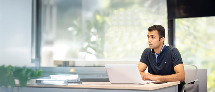 Image of a student sitting at a table with their laptop open in front of them