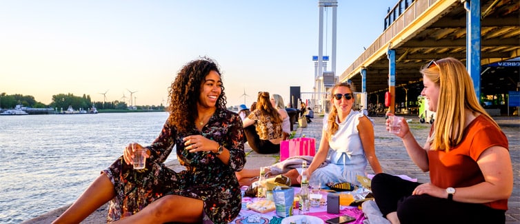 Image of students sat by the water smiling at each other